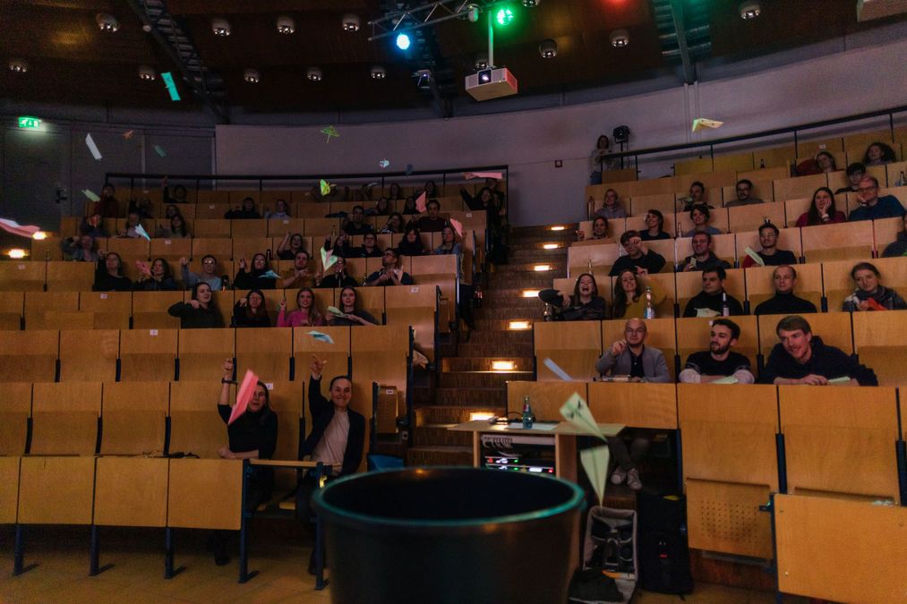 enlarge the image: People in a colourfully lit lecture hall